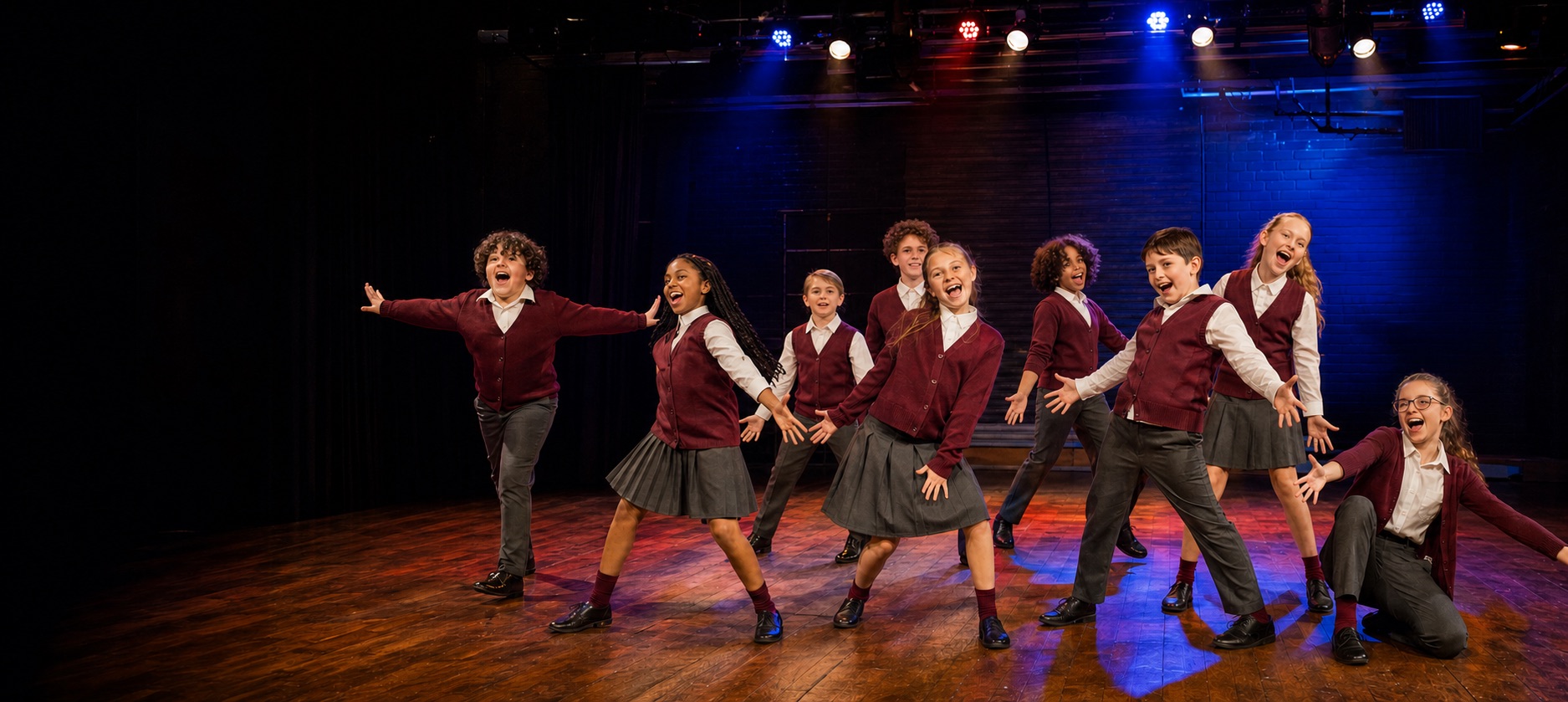 A joyful youth theatre company performing an energetic number under stage lights